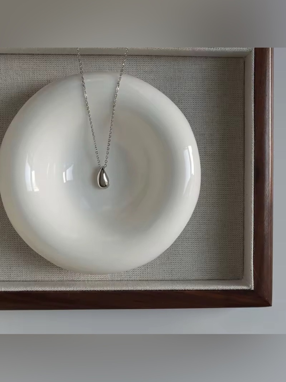 Silver Teardrop Necklace on White Ceramic Display - Unbranded